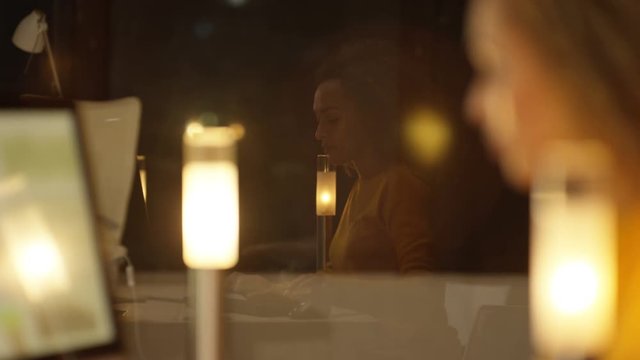  Close up woman working on computer at night with her face reflected in window