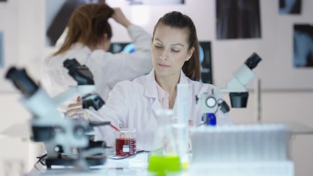 Scientific research team working in the lab, focus on woman experimenting with chemicals