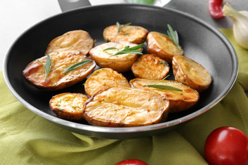 Delicious baked potatoes with rosemary in pan on table