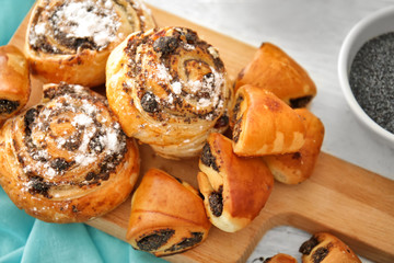 Tasty pastries with poppy seeds on wooden board