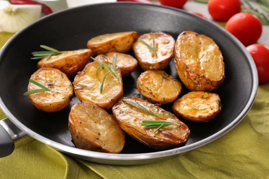 Delicious baked potatoes with rosemary in pan on cloth
