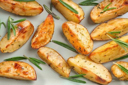 Delicious baked potatoes with rosemary on light background, closeup