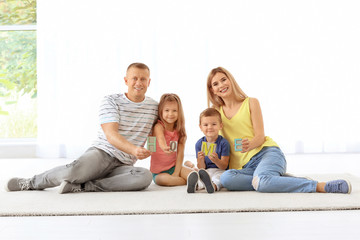 Happy family with word HOME sitting on floor in new apartment