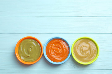 Bowls with baby food on wooden background