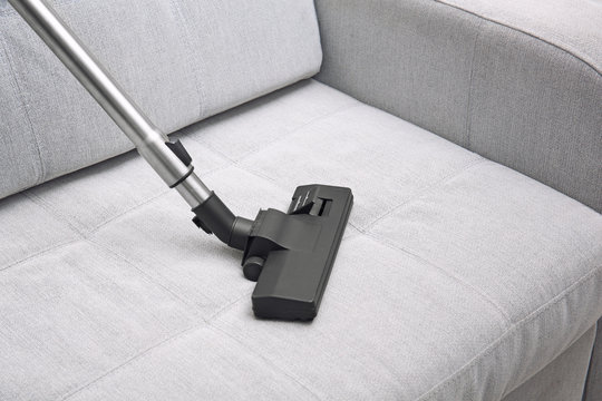 Cleaning sofa with vacuum cleaner at home