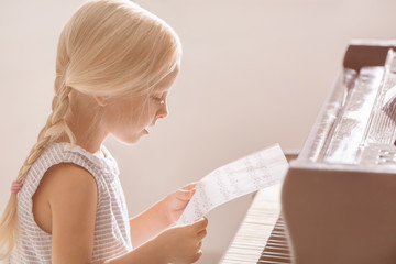 Little girl playing piano indoors