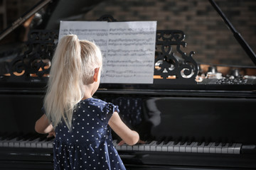 Little girl playing piano at concert indoors