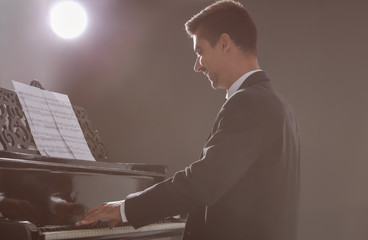 Young man playing piano at concert indoors