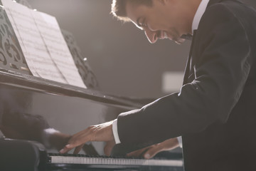 Young man playing piano at concert indoors