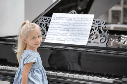 Little girl sitting near piano indoors