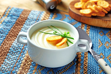 Ceramic bowl with potato cream soup on table