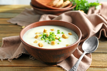 Bowl with potato cream soup on table