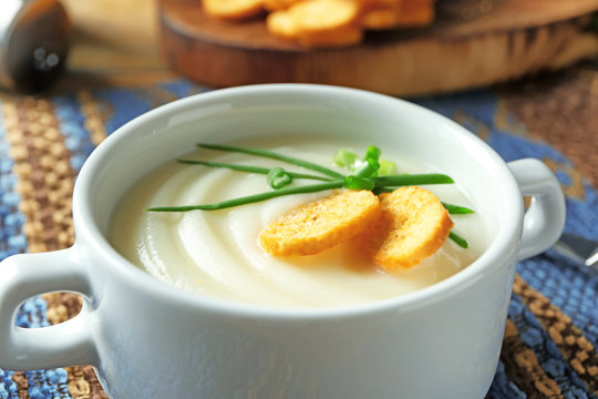 Ceramic bowl with potato cream soup on table