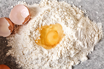 Heap of flour with egg on kitchen table