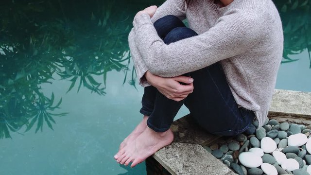 Cinemagraph of girl by the pool in a jumper on a cold day. Seamless video loop. Living Photo.