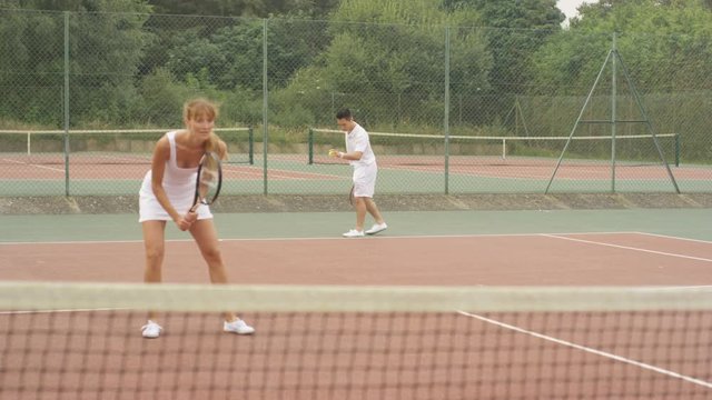  Mixed doubles tennis players enjoying a game on outdoor court in the summer. 