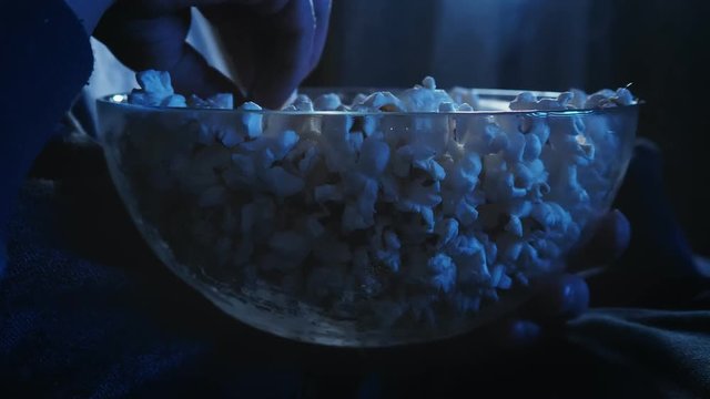 Hand reaching popcorn from a bowl while wathcing movie on TV
