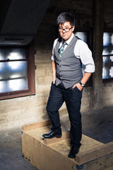 Young transgender man in formal clothing poses in a grungy urban location