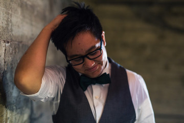 Young transgender man in formal clothing poses in a grungy urban location