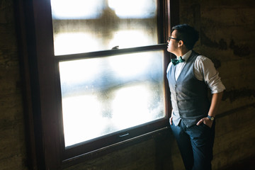 Fototapeta premium Young transgender man in formal clothing poses in a grungy urban location