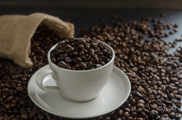 Roasted coffee beans in burlap sack bag on old rusty background