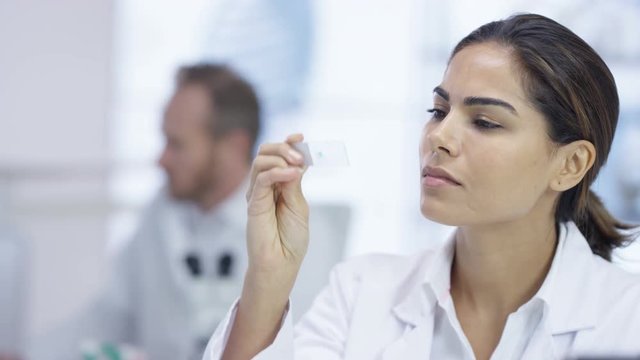 Close up medical researcher in the lab looking at a slide under microscope