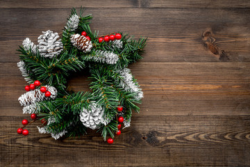 Christmas wreath woven of spruce branches with red berries on wooden background top view copyspace
