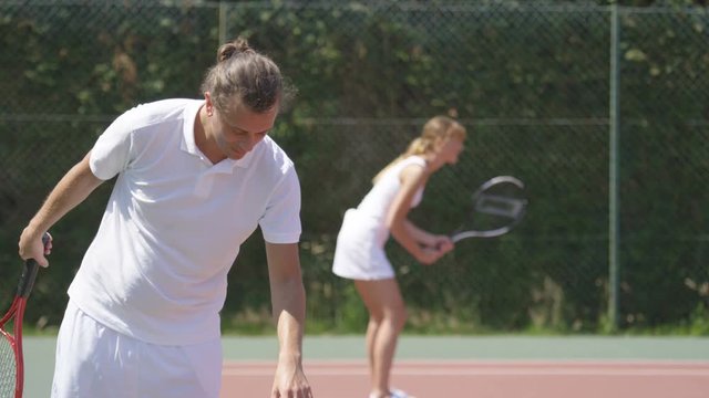  Male & female tennis players playing 2 different games on outdoor court