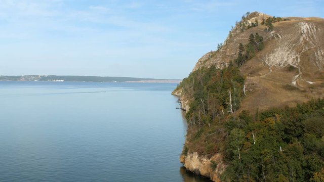 amazing cliff covered trees and grass near calm water of river in sunny day