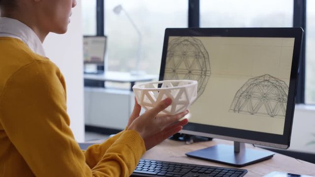  Designer working at her desk looking at 3D printed object