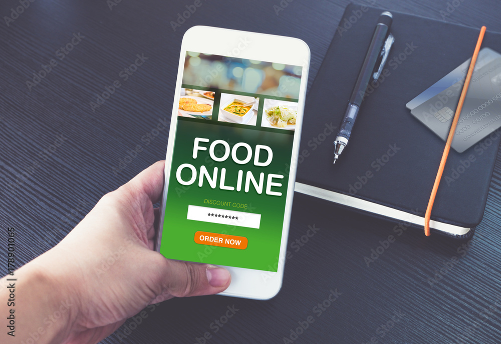 Poster hand holding mobile phone and order food online for app with promo code with credit card on notebook