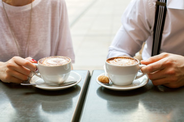 A man and woman  with a cappuccino Cup at a table in a cafe