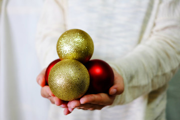 Hand holding gold and red ornament with white sweater