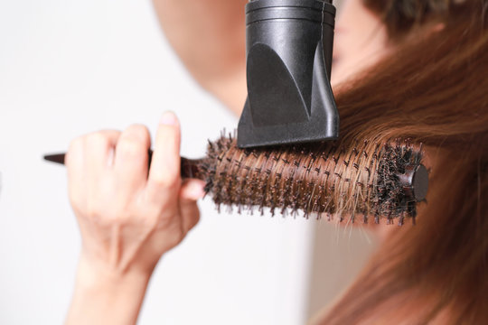 Drying Brown hair with hair dryer and round brush.