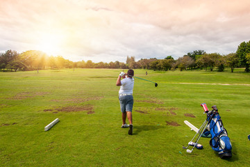 13-year-old Asian boy playing golf on a golf course in the sun