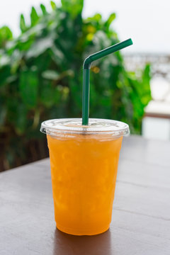 Orange juice  in a plastic glass placed on a wooden table.