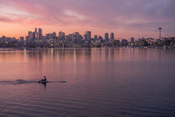 Rowers glide by on the calm waters of Lake Union as dawn breaks on the Seattle skyline