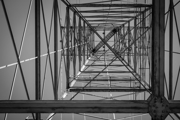 Black and white of looking up from inside of an electrical tower