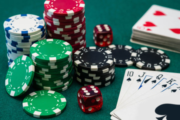 Poker chips, dice and Royal Flush card combination on green table	