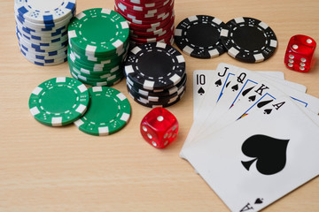 Poker chips, dice and Royal Flush card combination on wooden table