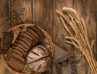 Fototapeta na wymiar Sliced bread in a wicker tray with spikelets wooden surface with cloth