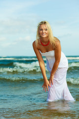 Fototapeta na wymiar Blonde woman wearing dress playing with water