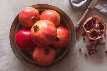 Ripe pomegranate on a metallic plate on a dark background