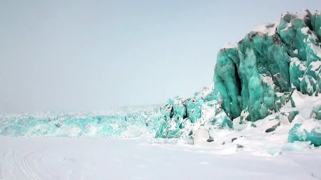 Glacier of beautiful unique turquoise color on background of snow in Arctic. Amazing ice desert landscape. Silence quiet of wilderness North Pole Way to Pyramid on Spitsbergen Svalbard in Norway.