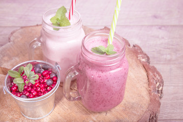 Assorted fruit or berry milk shakes in mason jar on wooden desk and table. Smoothie healthy eating concept