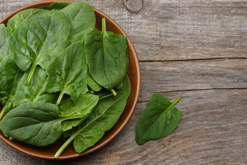 spinach leaves in bowl on dark wooden table top view