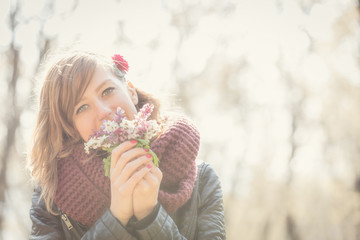 Cute young girl smelling nice bouquet of flowers in nature.