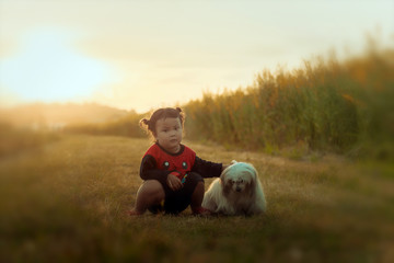 Little girl with the dog, smiling at camera in the garden; light and lens flare effect tone.