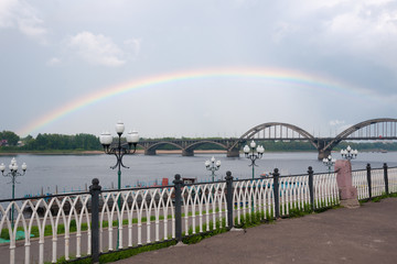 Fototapeta na wymiar Rainbow over embankment and bridge of the Volga River in Rybinsk in summer, Yaroslavl Region, Russia