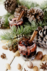 glass of hot mulled wine for the new year with ingredients for cooking, nuts and Christmas decorations